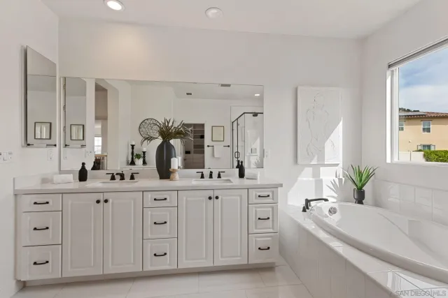 a spacious bathroom with a double vanity sink a mirror a bathtub and window