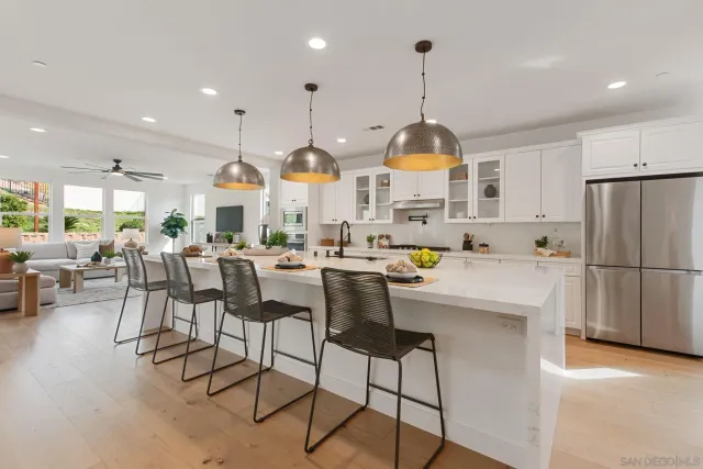 a kitchen with stainless steel appliances kitchen island granite countertop a table chairs and a white cabinets