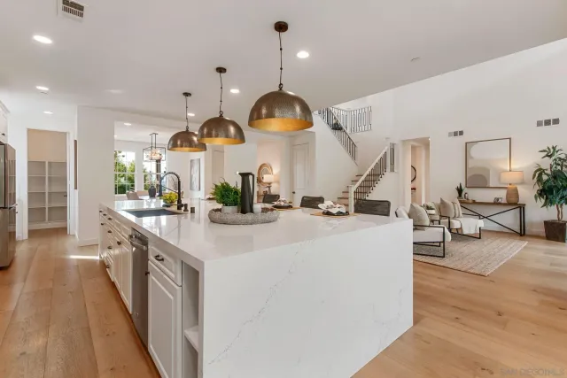 a large kitchen with stainless steel appliances kitchen island a large counter top a sink a stove and a wooden floors