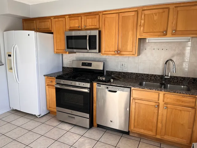 a kitchen with granite countertop a refrigerator stove and microwave