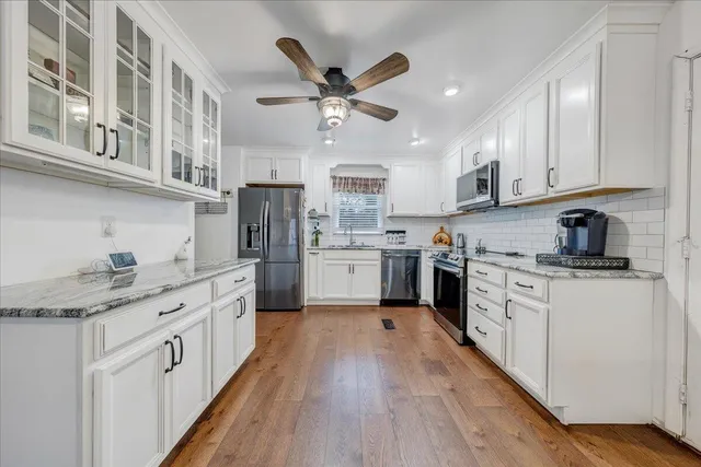 a kitchen with stainless steel appliances granite countertop a sink cabinets and wooden floor
