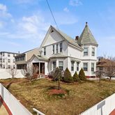 a view of a white house next to a yard