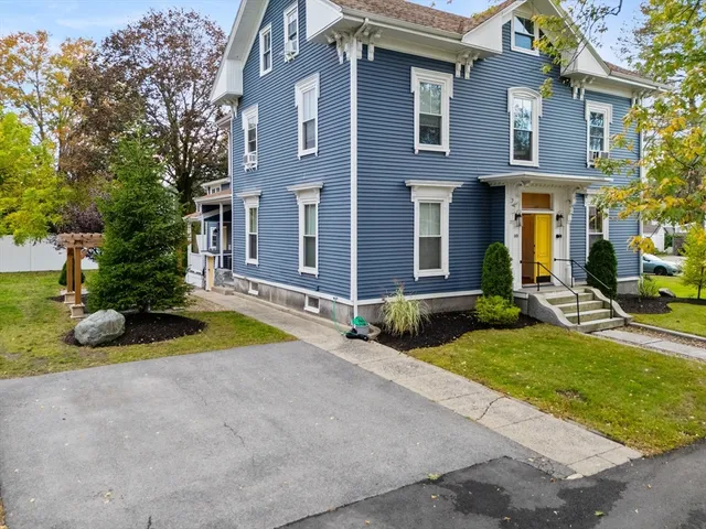 a view of brick house with a yard and large tree