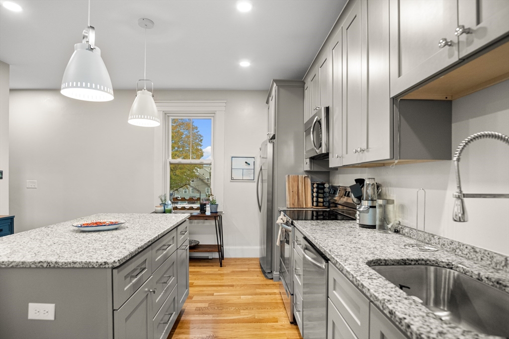 149 High Street, Unit 4 Danvers, MA 01923 - Photo 7 of 33 a kitchen with granite countertop cabinets a sink a window and stainless steel appliances