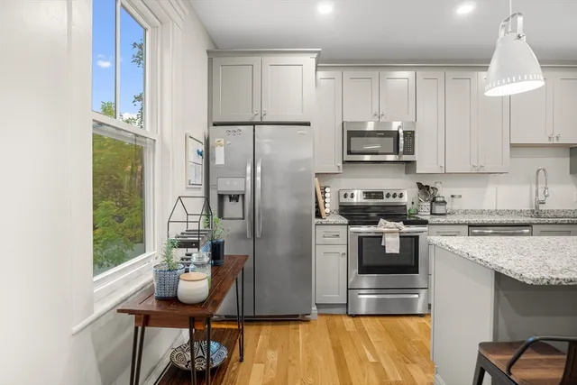 a kitchen with stainless steel appliances granite countertop a refrigerator a stove a sink dishwasher and white cabinets with wooden floor