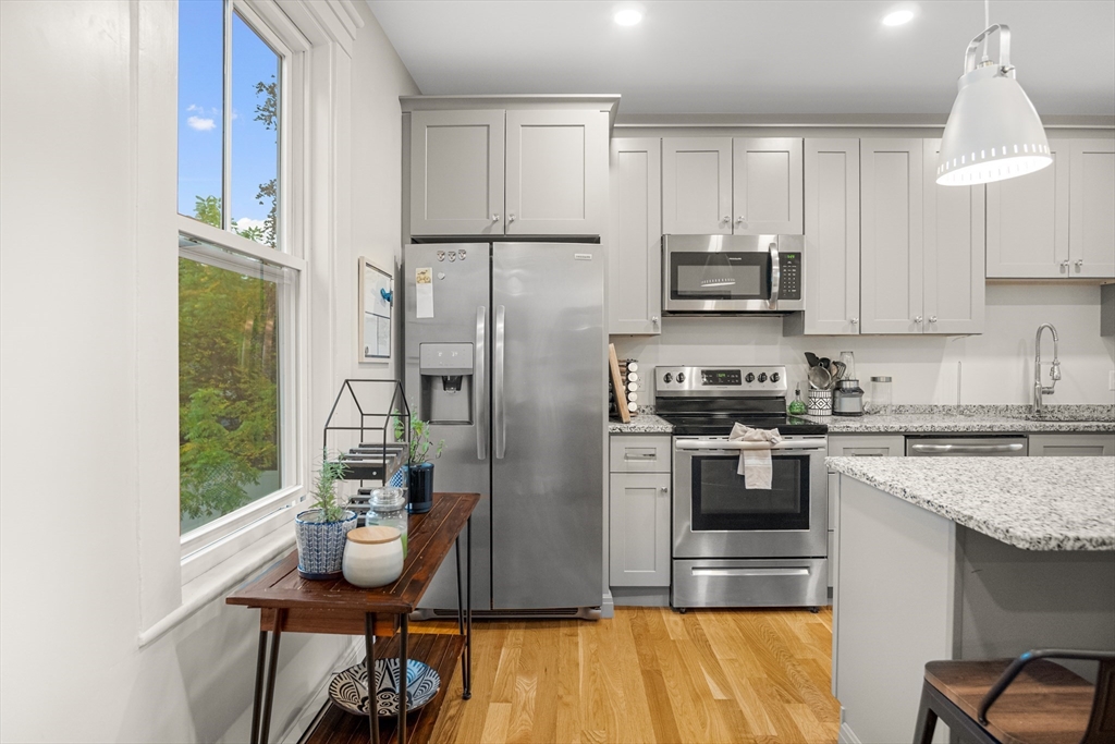 149 High Street, Unit 4 Danvers, MA 01923 - Photo 9 of 33 a kitchen with stainless steel appliances granite countertop a refrigerator a stove a sink dishwasher and white cabinets with wooden floor