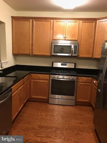 a kitchen with stainless steel appliances granite countertop white cabinets and a stove top oven