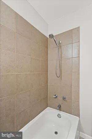 a bathroom with a bathtub shower sink mirror and toilet