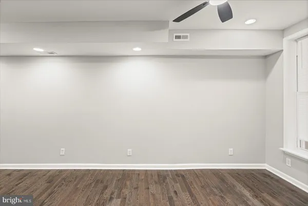 an empty room with wooden floor and natural light