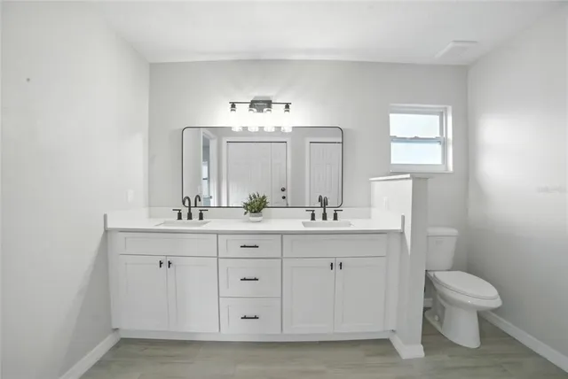 a bathroom with a toilet a sink a mirror and vanity
