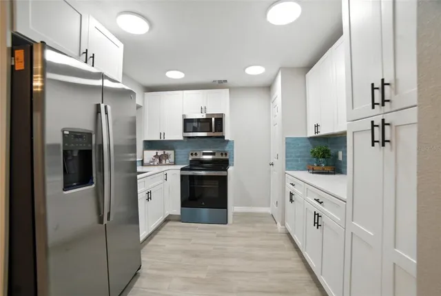 a kitchen with white cabinets and stainless steel appliances