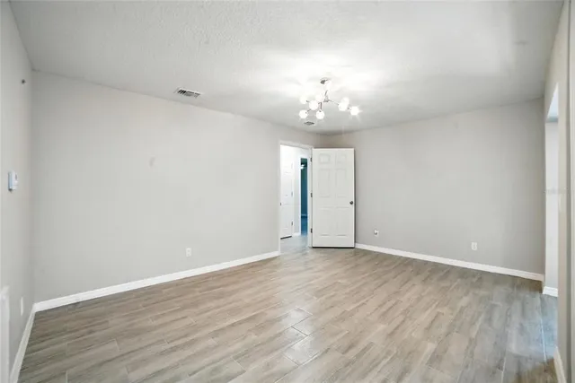 a view of an empty room with wooden floor and chandelier