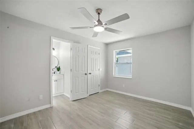 an empty room with wooden floor fan and windows