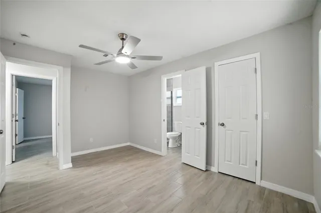 an empty room with wooden floor and a ceiling fan