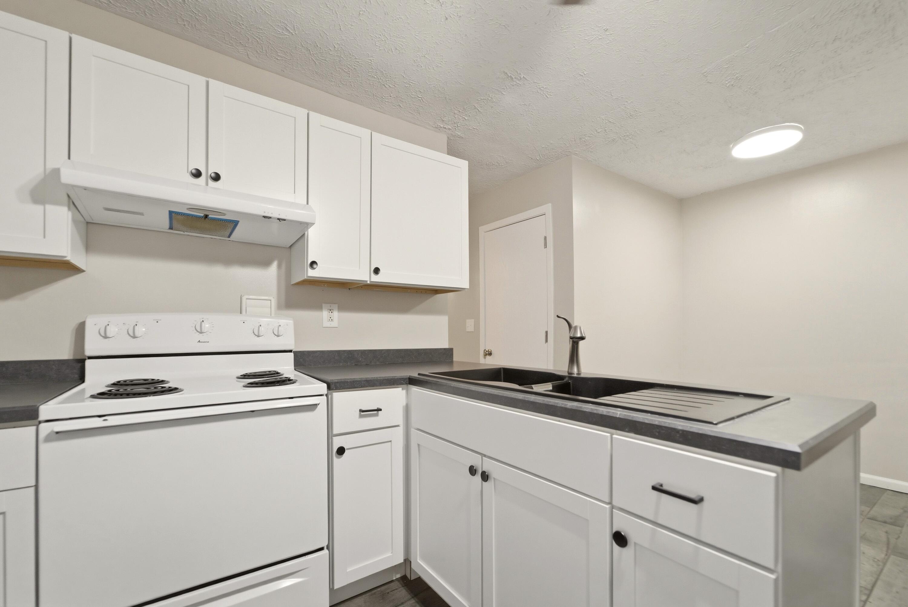 140 Sycamore Court, Unit 142 Hebron, IN 46341 - Photo 5 of 11 a kitchen with white cabinets and white appliances