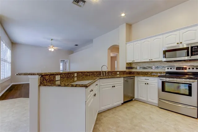 an empty room with a chandelier fan and windows