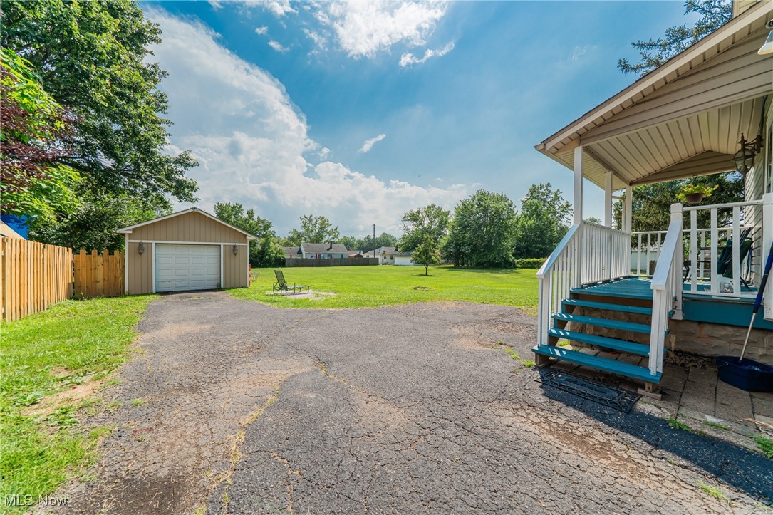 13614 Granger Road Cleveland, OH 44125 - Photo 33 of 38 View of yard with an outdoor structure, a garage, and asphalt driveway
