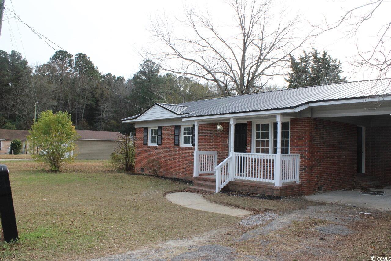 105 Mace Court Latta, SC 29565 - Photo 3 of 12 View of front of house with crawl space, a front yard, brick siding, covered porch, and a metal roof