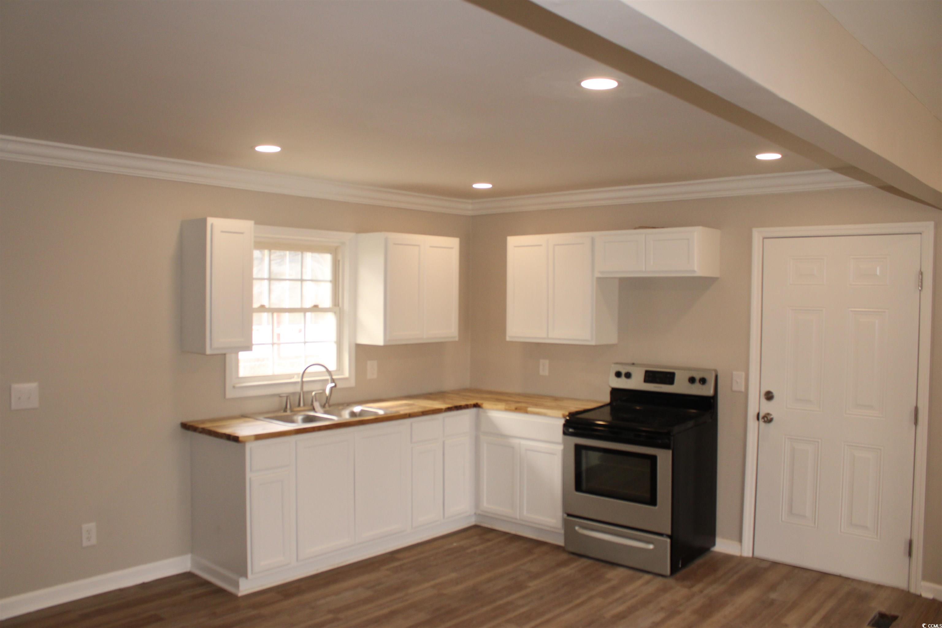 105 Mace Court Latta, SC 29565 - Photo 5 of 12 Kitchen featuring stainless steel range with electric cooktop, white cabinetry, dark wood-type flooring, wood counters, and crown molding