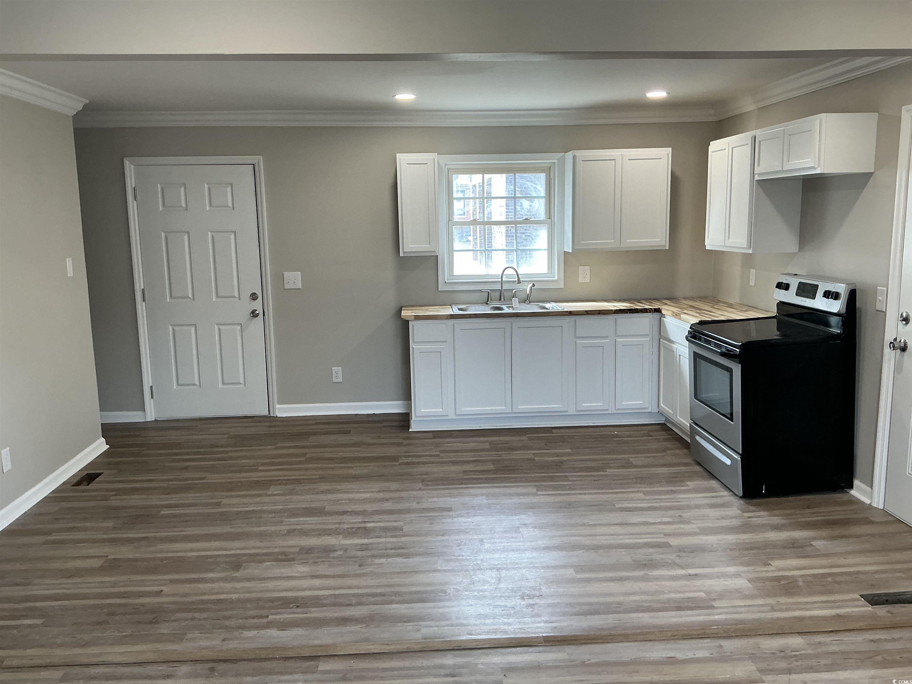 105 Mace Court Latta, SC 29565 - Photo 6 of 12 Kitchen featuring stainless steel range with electric stovetop, white cabinetry, ornamental molding, dark wood-style flooring, and wooden counters