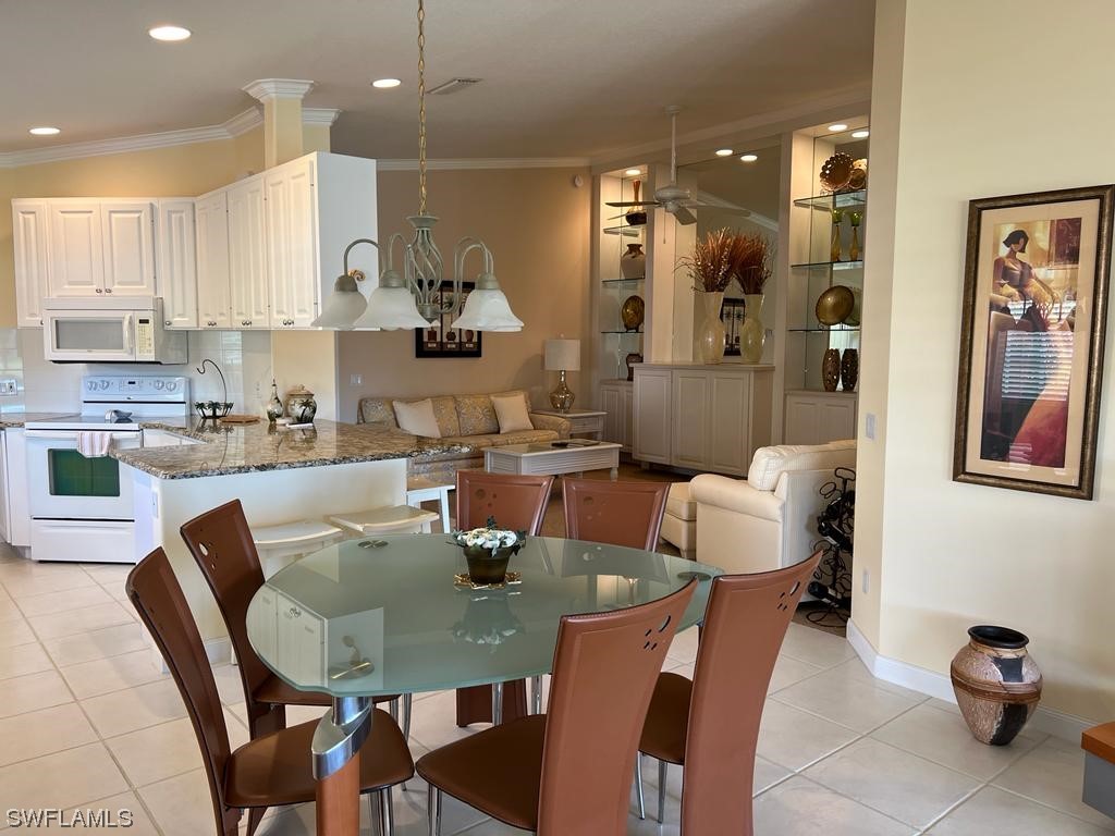 a dining room with stainless steel appliances kitchen island granite countertop a dining table chairs and a refrigerator
