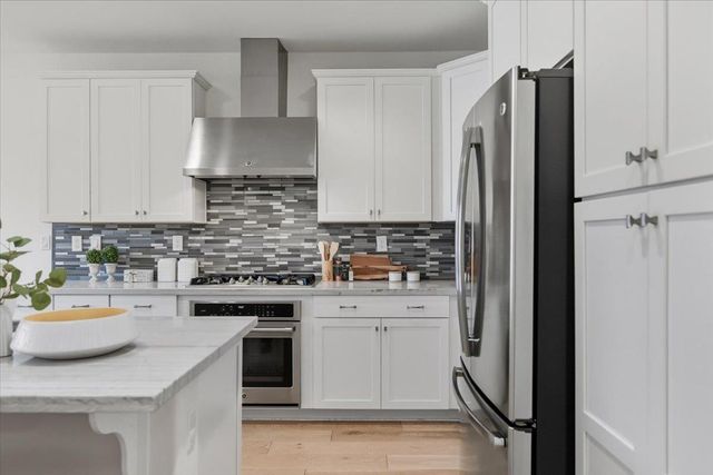 a view of a house with potted plants and a bench in front of house