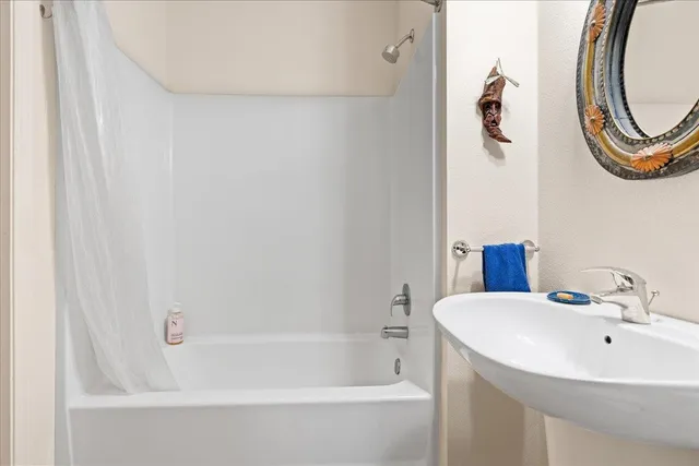 a white bath tub sitting next to a white sink and a mirror