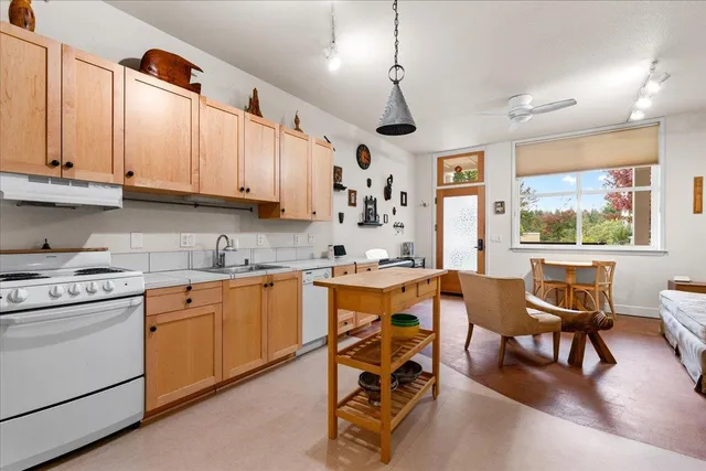 a kitchen with stainless steel appliances granite countertop a stove a sink dishwasher a dining table and chairs with wooden floor