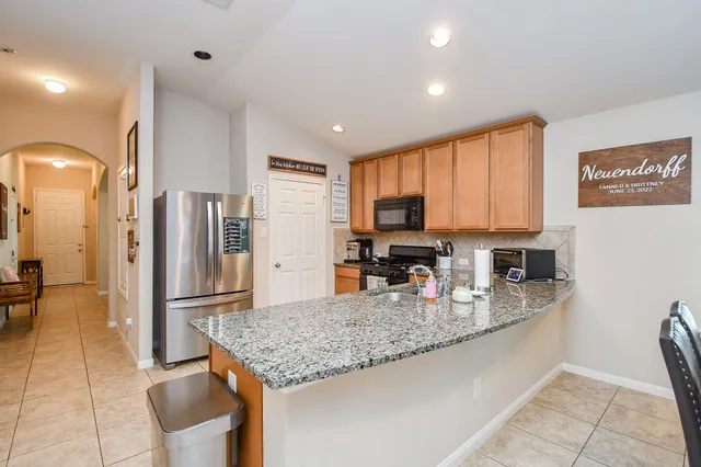 a kitchen with stainless steel appliances granite countertop a refrigerator stove top oven and sink