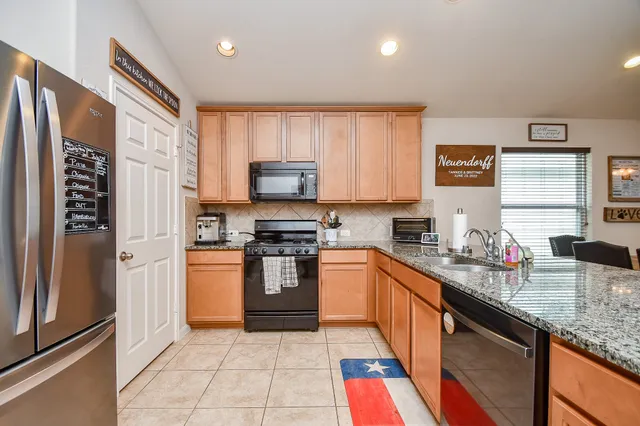 a large kitchen with stainless steel appliances granite countertop lots of counter top space and a sink