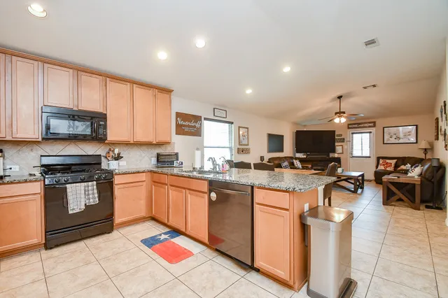 a kitchen with granite countertop a sink a counter top space and stainless steel appliances