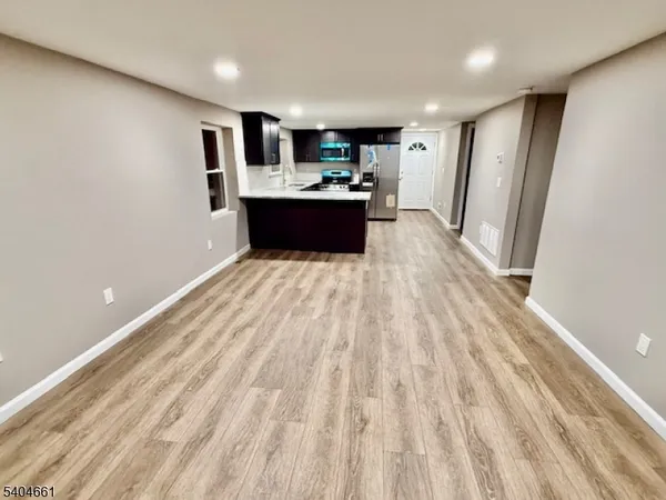 a large white kitchen with wooden floors and stainless steel appliances