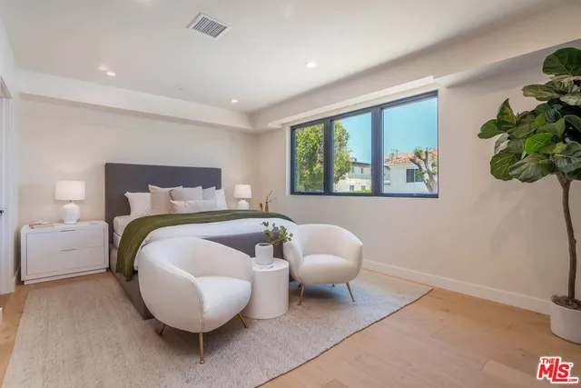 a spacious bedroom with a bed painting on wall and a potted plant