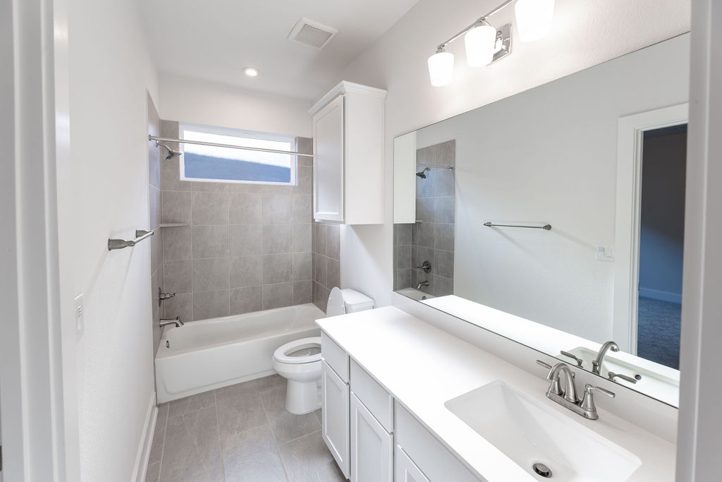 6414 Cowman Way Austin, TX 78747 - Photo 10 of 35 A crisp white vanity and tiled tub surround define this modern secondary bathroom.
