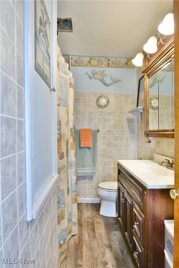 3224 Reeves Road Northeast Warren, OH 44483 - Photo 31 of 49 Bathroom with vanity, curtained shower, dark wood-style flooring, and tile walls