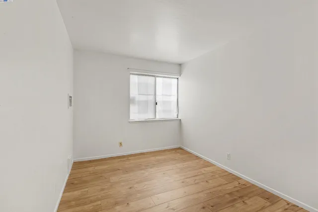 an empty room with wooden floor and window