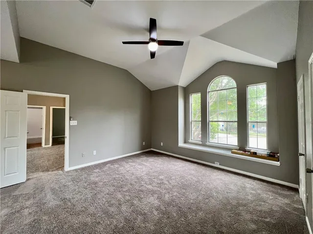 an empty room with large windows and ceiling fan