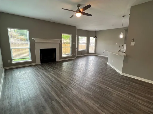 an empty room with wooden floor fireplace and windows