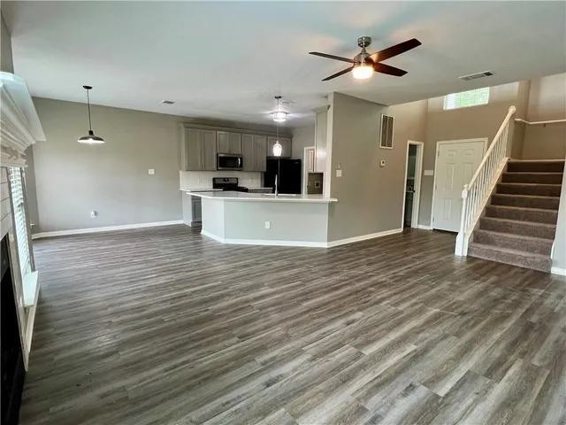 a view of kitchen and empty room with wooden floor