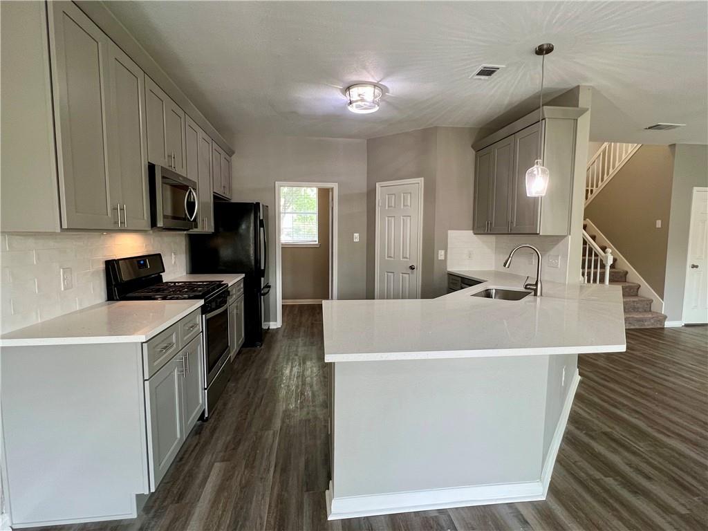 1706 Winners Ribbon Circle Pflugerville, TX 78660 - Photo 5 of 21 a kitchen with stainless steel appliances a white stove top oven a sink dishwasher and a refrigerator with wooden floor
