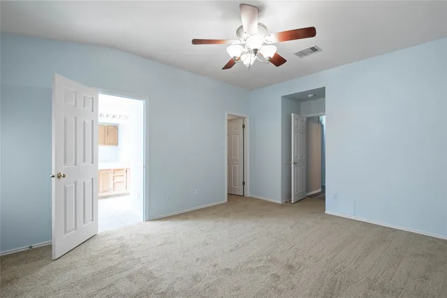 a view of an empty room with a chandelier fan
