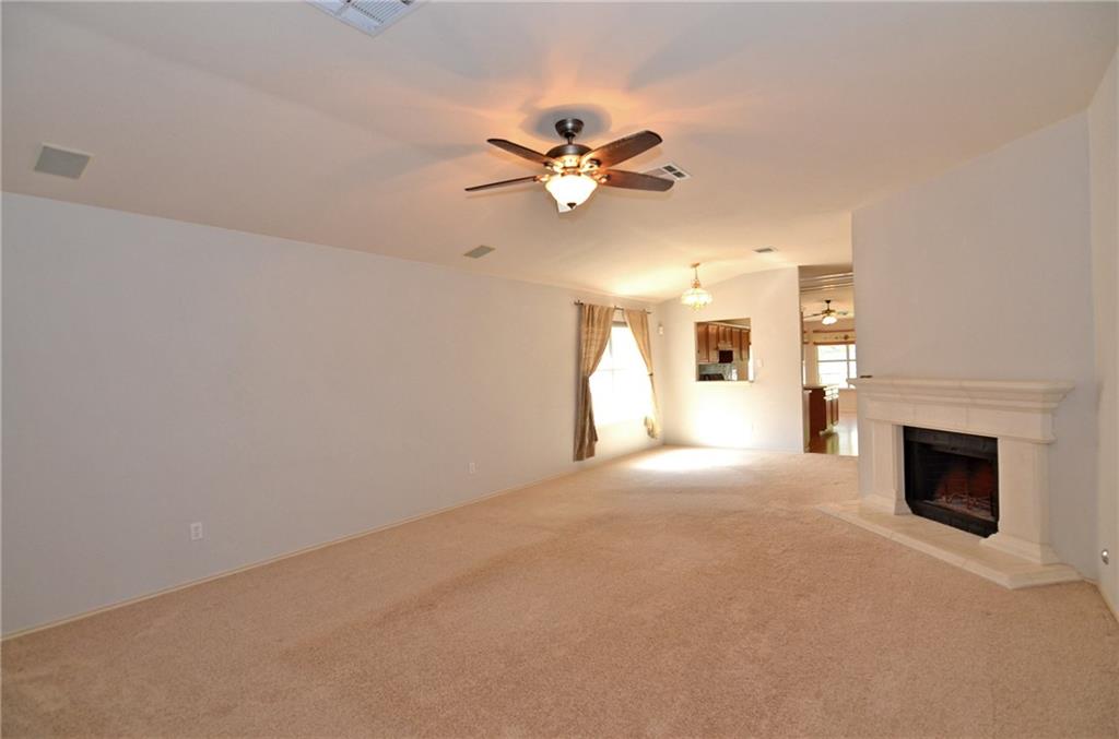 3609 Ruby Red Drive Austin, TX 78728 - Photo 2 of 21 Unfurnished living room with ceiling fan, carpet, and a fireplace with raised hearth