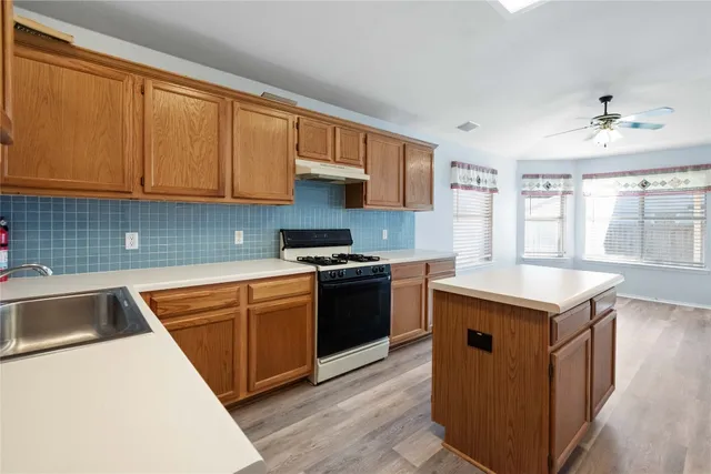 a kitchen with granite countertop a sink dishwasher stove and cabinets