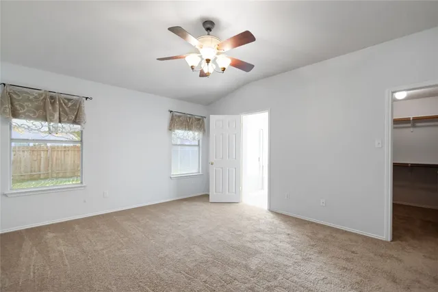an empty room with chandelier fan and windows