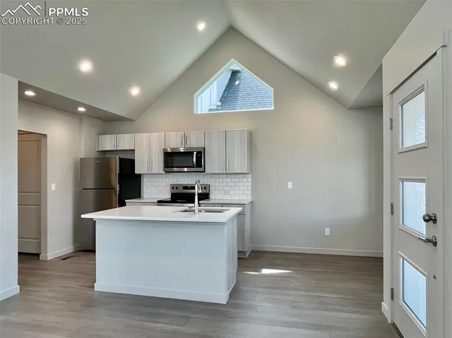 a kitchen with kitchen island a sink a stove a refrigerator and a cabinets