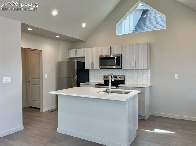 a kitchen with kitchen island a white counter top space cabinets and stainless steel appliances