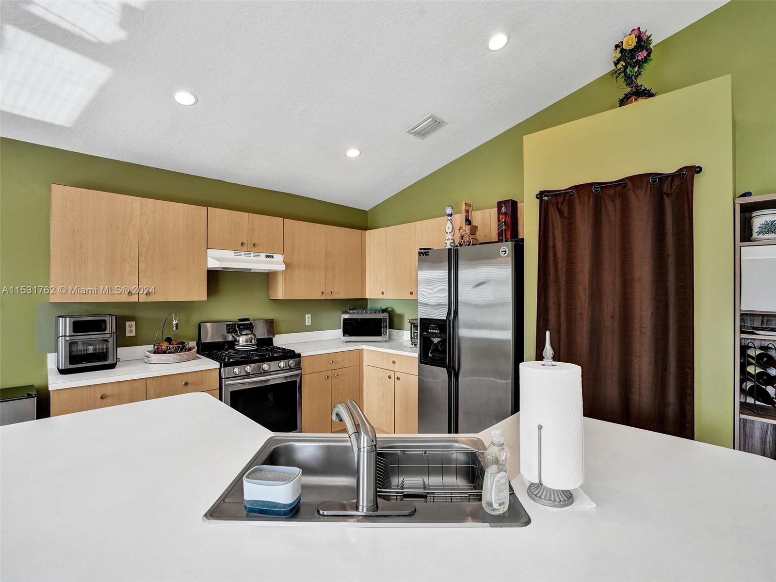 Greenacres Greenacres, FL 33413 - Photo 11 of 61 a kitchen with stainless steel appliances a refrigerator a stove a sink a dining table and chairs