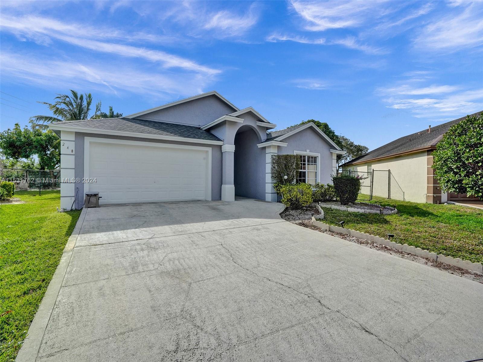 Greenacres Greenacres, FL 33413 - Photo 2 of 61 a front view of a house with a yard and garage