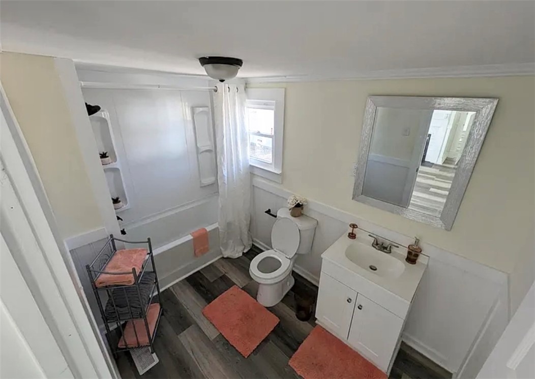 208 Hampton Street Iva, SC 29655 - Photo 16 of 19 This bright bathroom features a vanity, bathtub, and wood-look flooring, creating a clean and functional space.