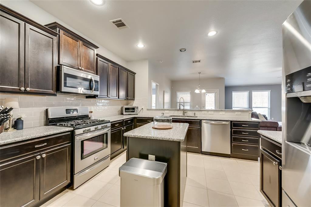 3406 Van Zandt Road Melissa, TX 75454 - Photo 3 of 6 a kitchen with stainless steel appliances granite countertop a stove top oven a sink dishwasher a dining table and chairs with wooden cabinets